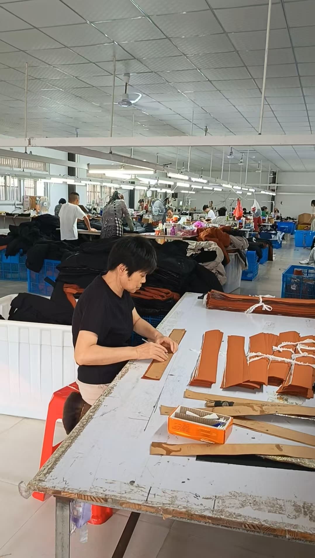 Worker handling cut fabric pieces at a workshop table